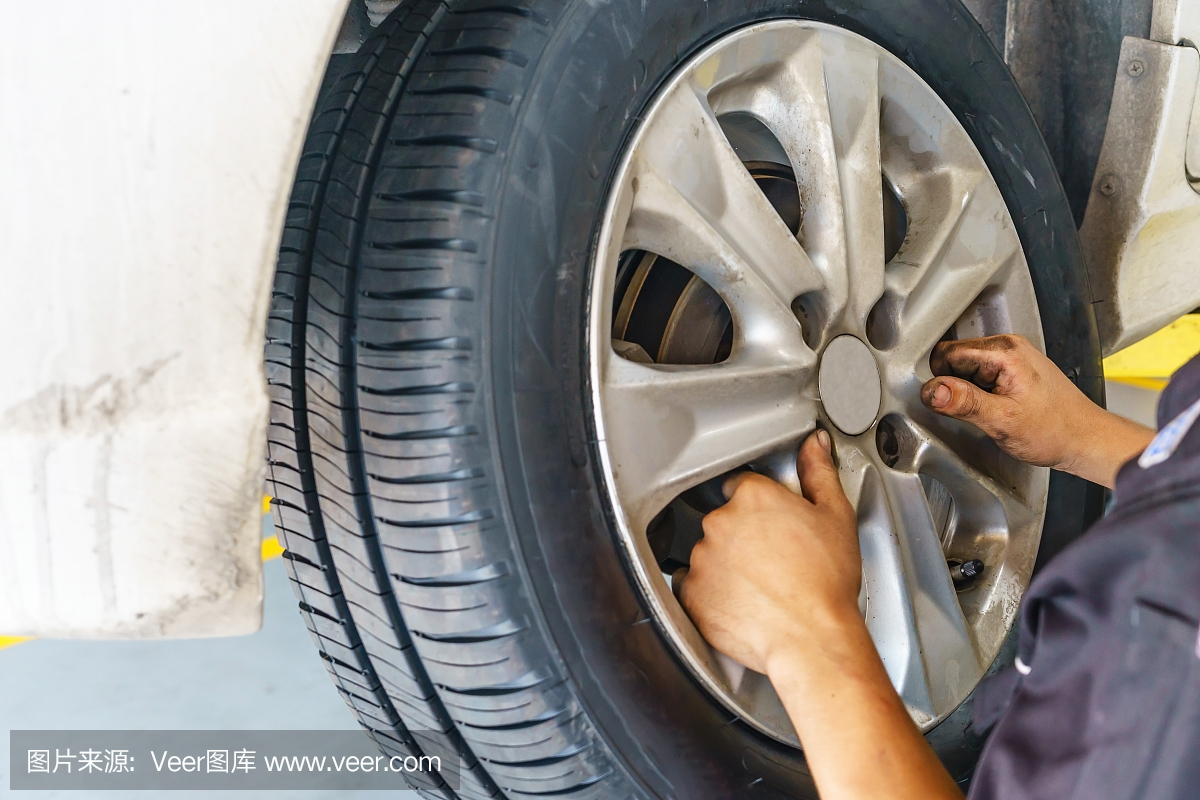 汽車(chē)服務(wù),修理,維護(hù)和人的概念-汽車(chē)技工與電動(dòng)螺絲刀在車(chē)間換輪胎
