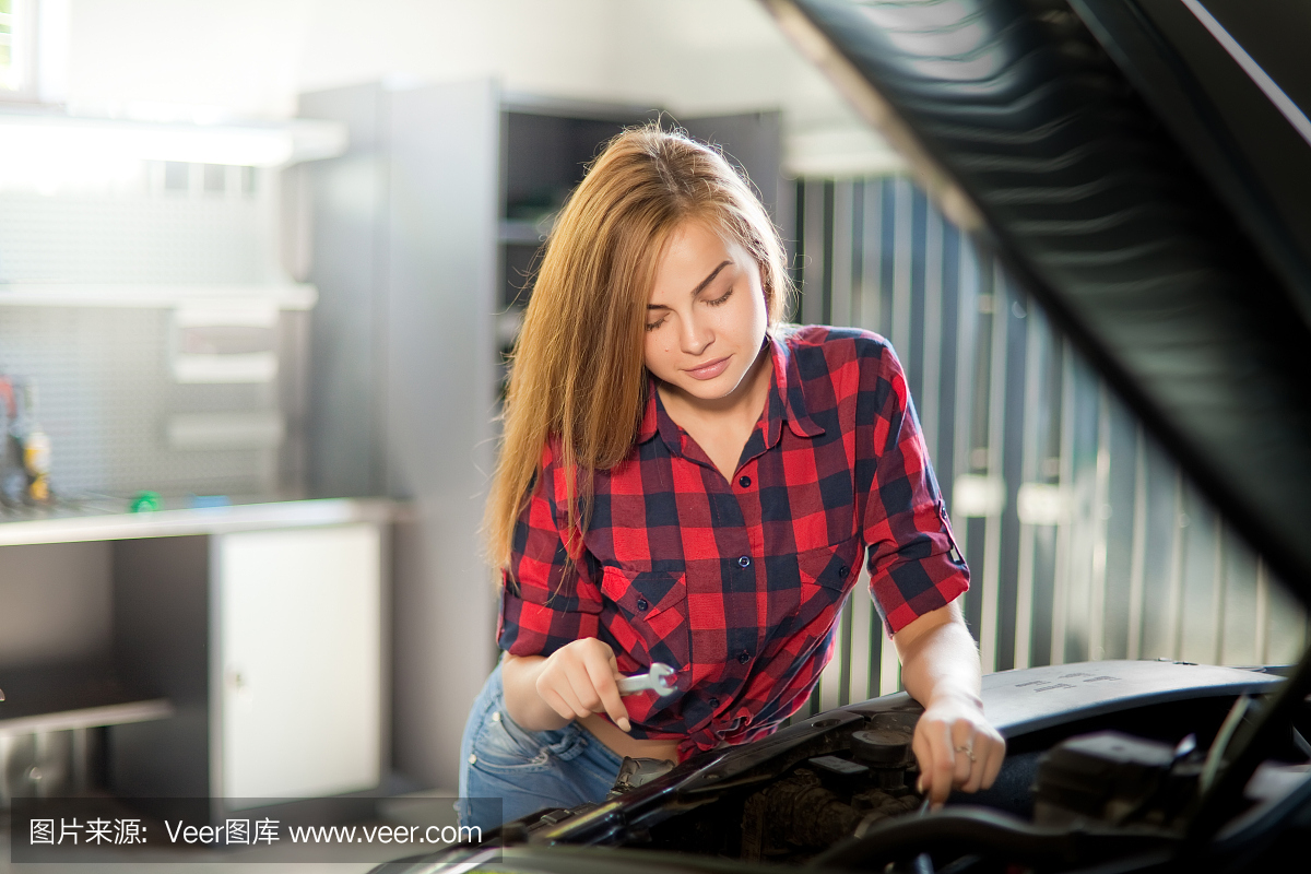 年輕性感的褐發(fā)機修工穿著格子襯衫在車庫里。